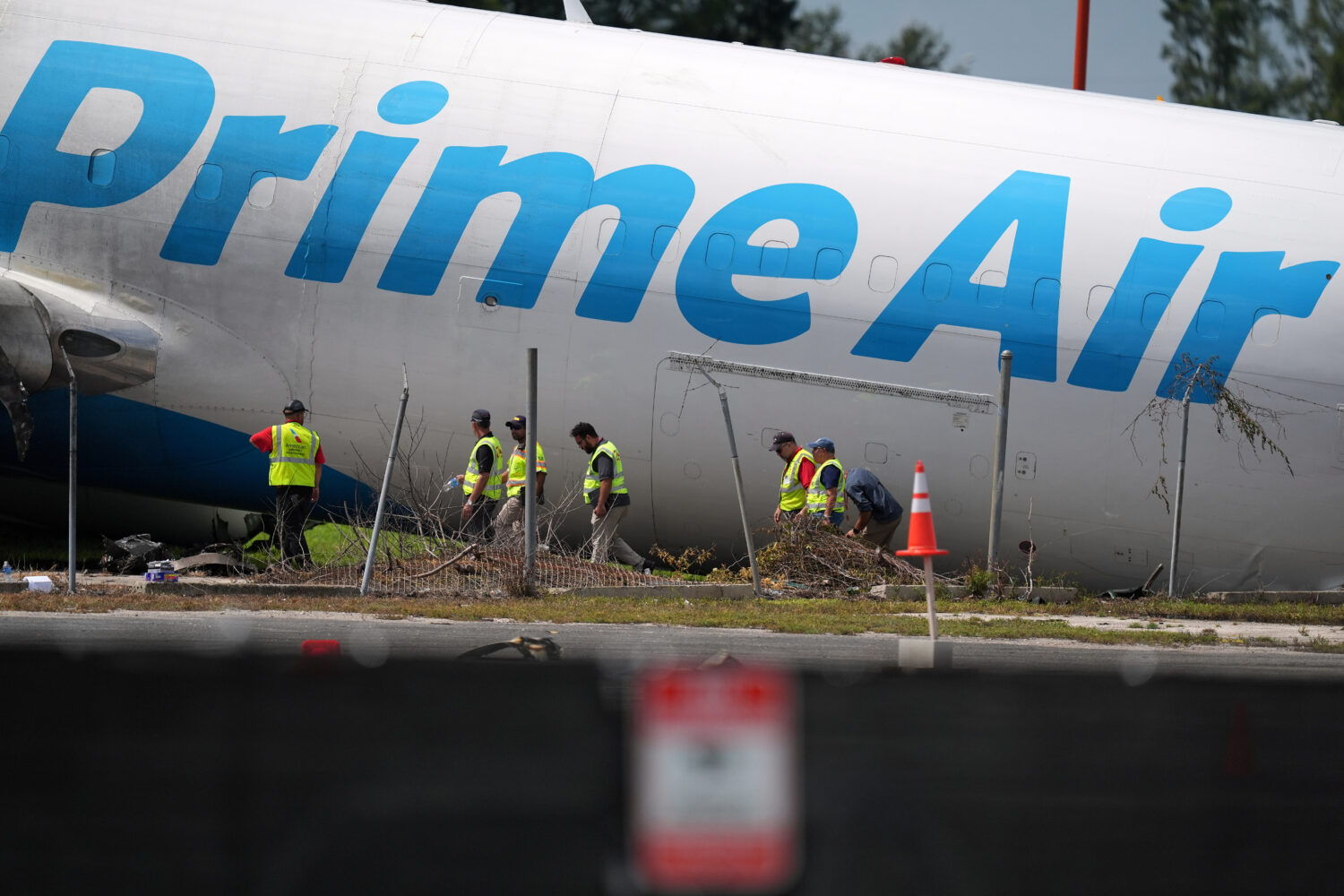 Workers inspect an Amazon cargo plane two days after it overshot a runway at Miami International Ai...