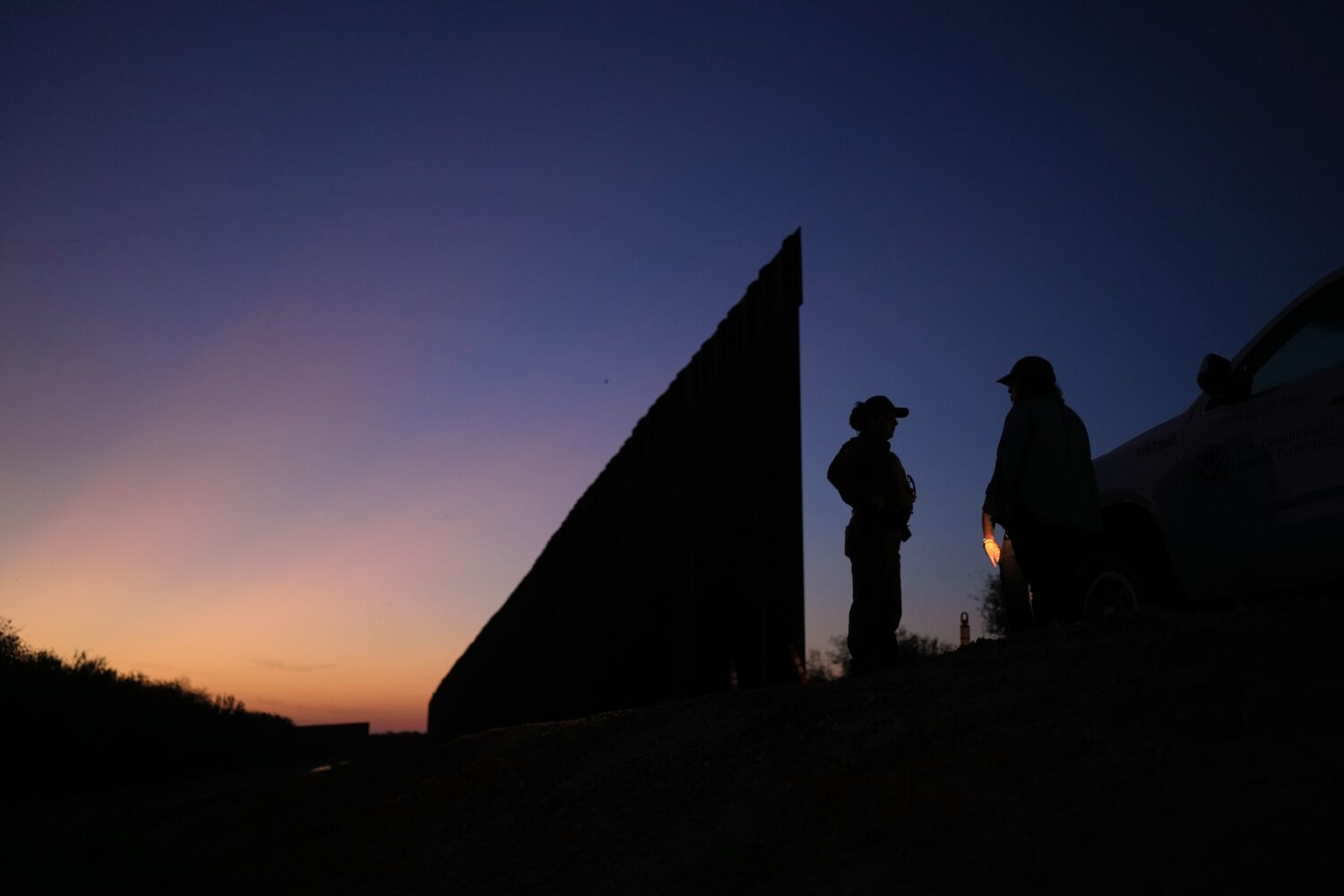 A U.S. Border Patrol agent stands near a new section of border wall at the Santa Ana Wildlife Refug...