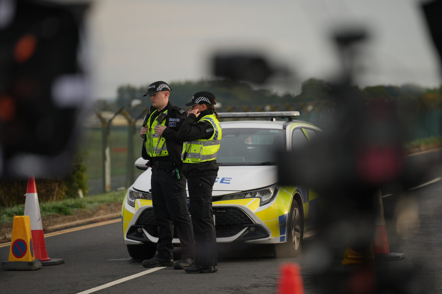Police officers guard a road leading to RAF Fairford, after an incident in Fairford, England, Monda...