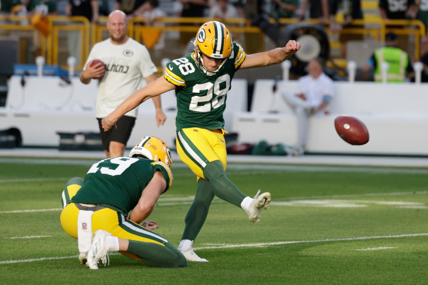 Green Bay Packers place kicker Trey Smack kicks with Daniel Whelan holding a preseason NFL football...