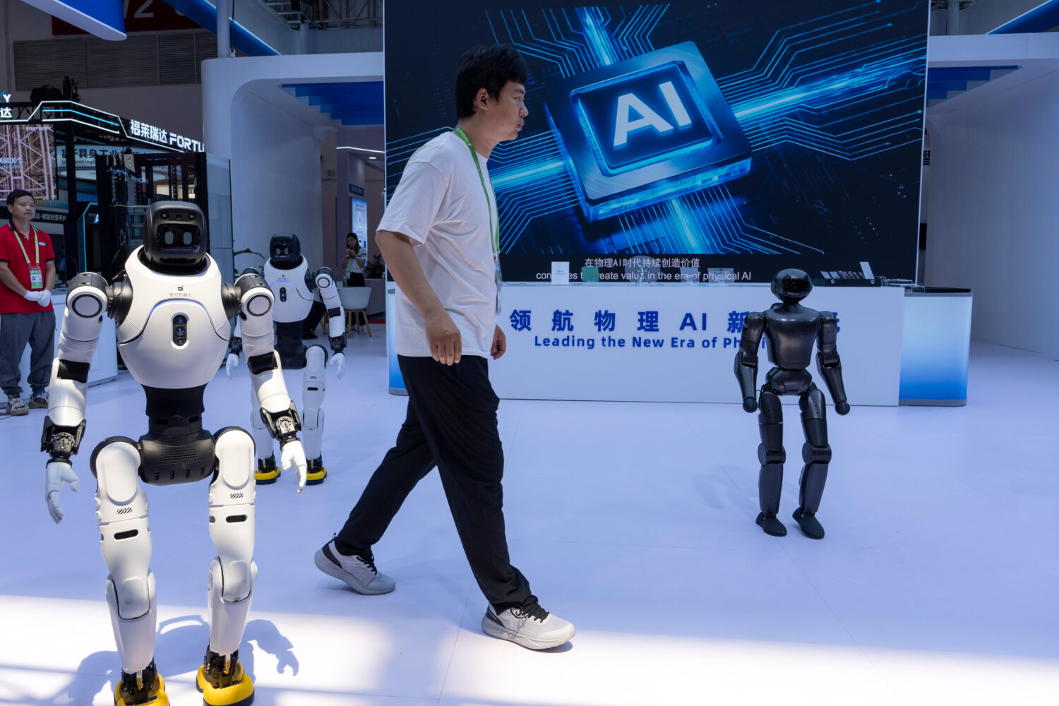 FILE- A worker passes by robots from Chinese company Lens at the China International Supply Chain E...