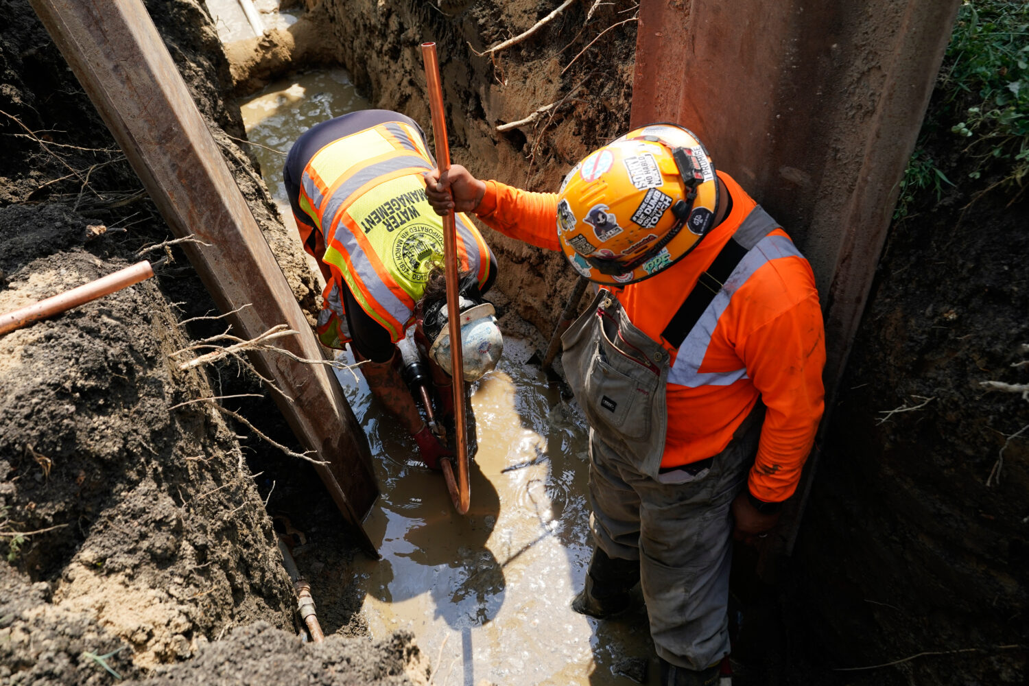 Workers install a copper pipe to replace a lead service line that brings drinking water to homes Tu...