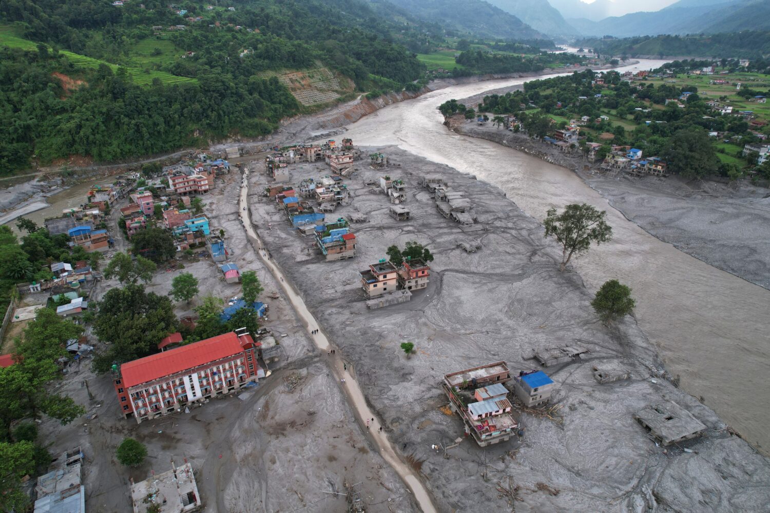 FILE - Homes are engulfed in mud in the aftermath of flash flooding along the Trishuli River in the...