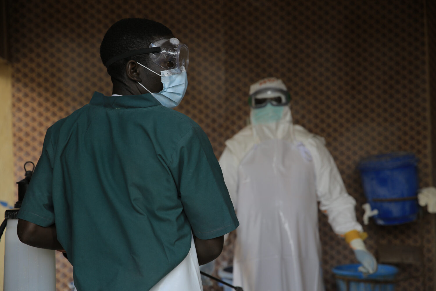 A healthcare worker is disinfected by his colleague inside a treatment center for Ebola patients in...