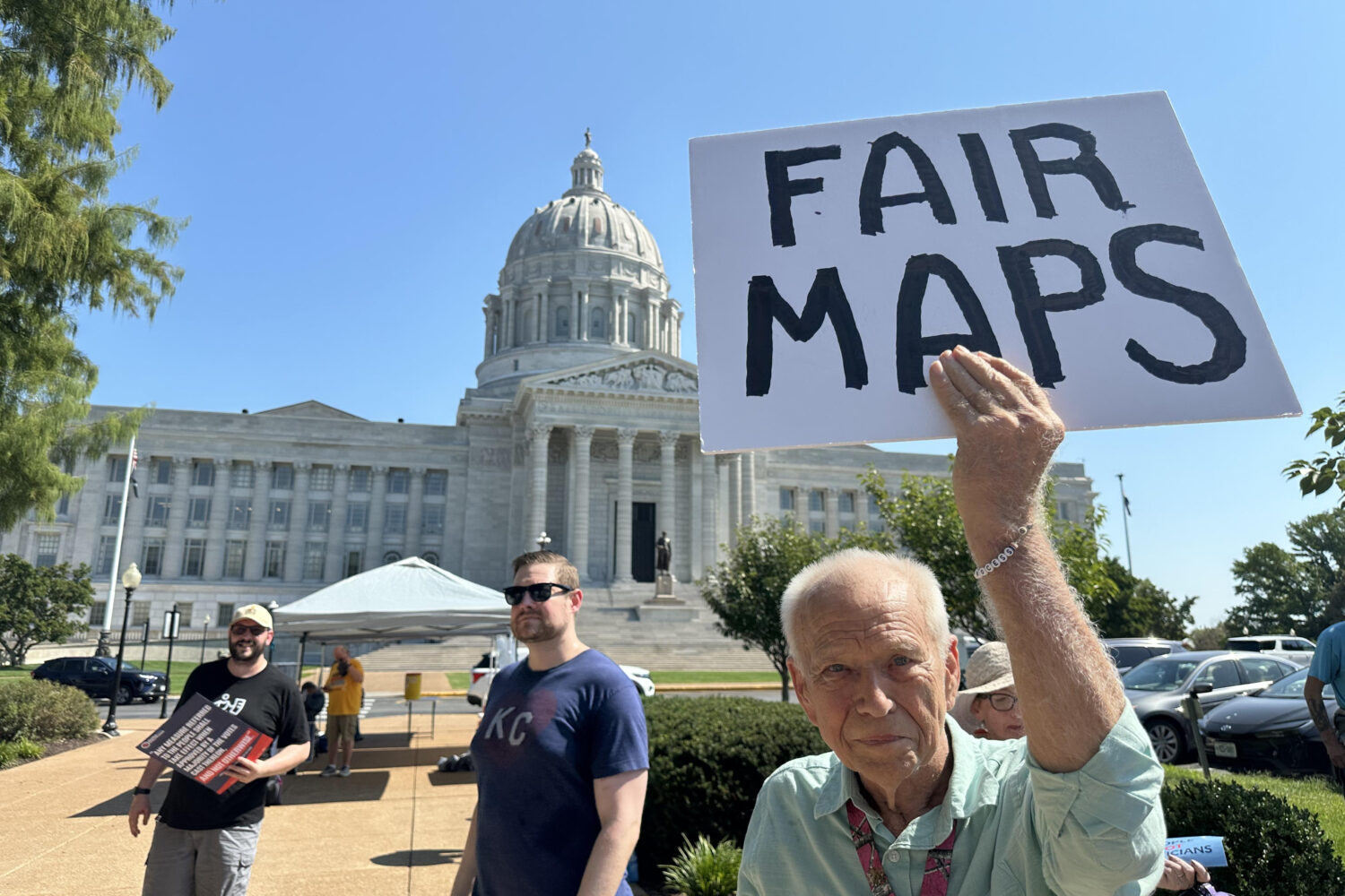 This photo taken with a smartphone shows Steve Perry, of Kansas City, holding a sign in opposition ...