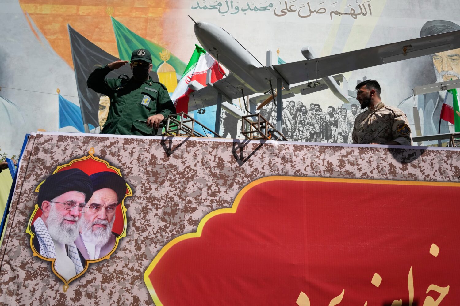 A member of Iran's Revolutionary Guard salutes while riding on a float displaying drones during the...