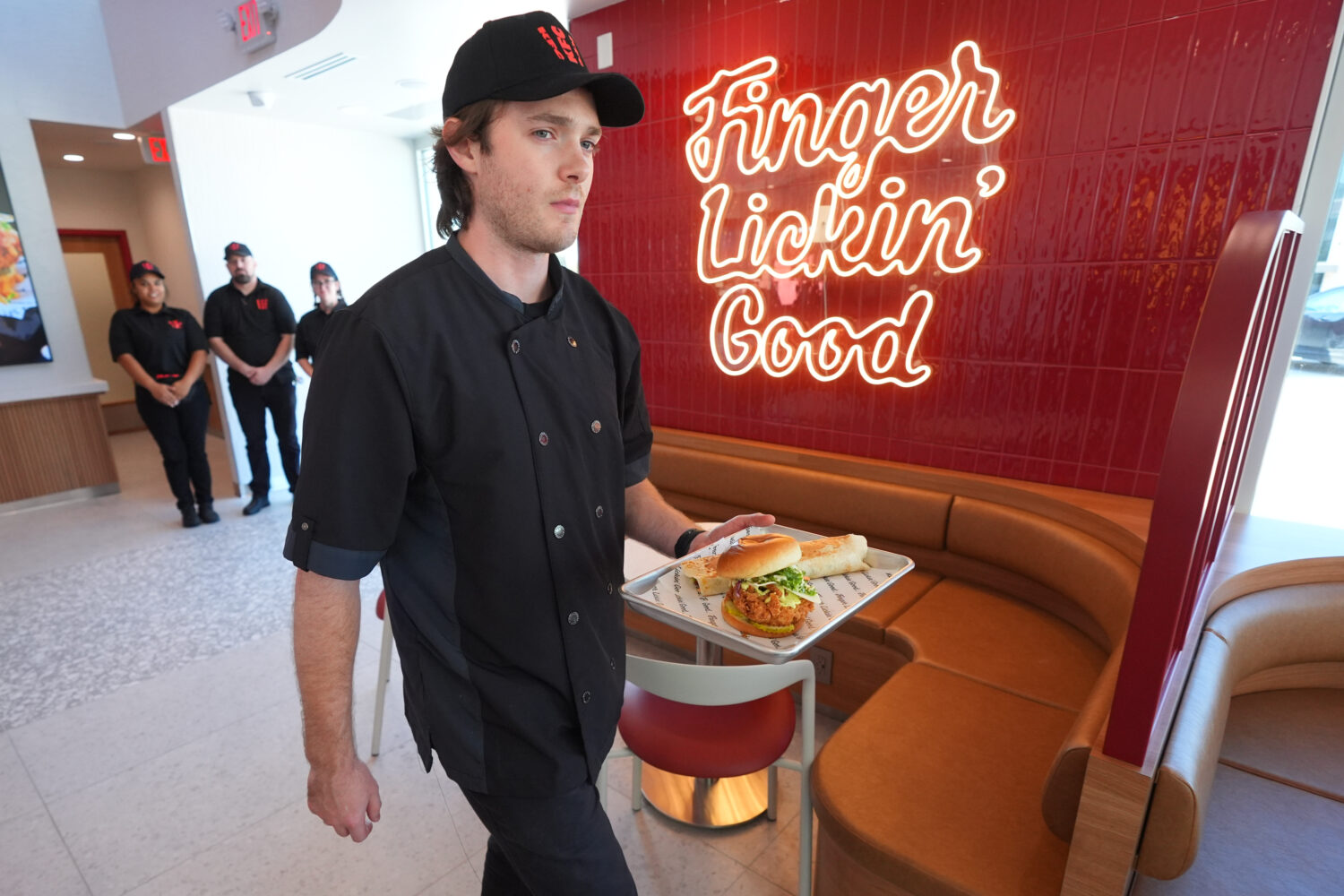 Jacob Mitchell carries a tray of food at new KFC restaurant pre-opening presentation in McKinney, T...