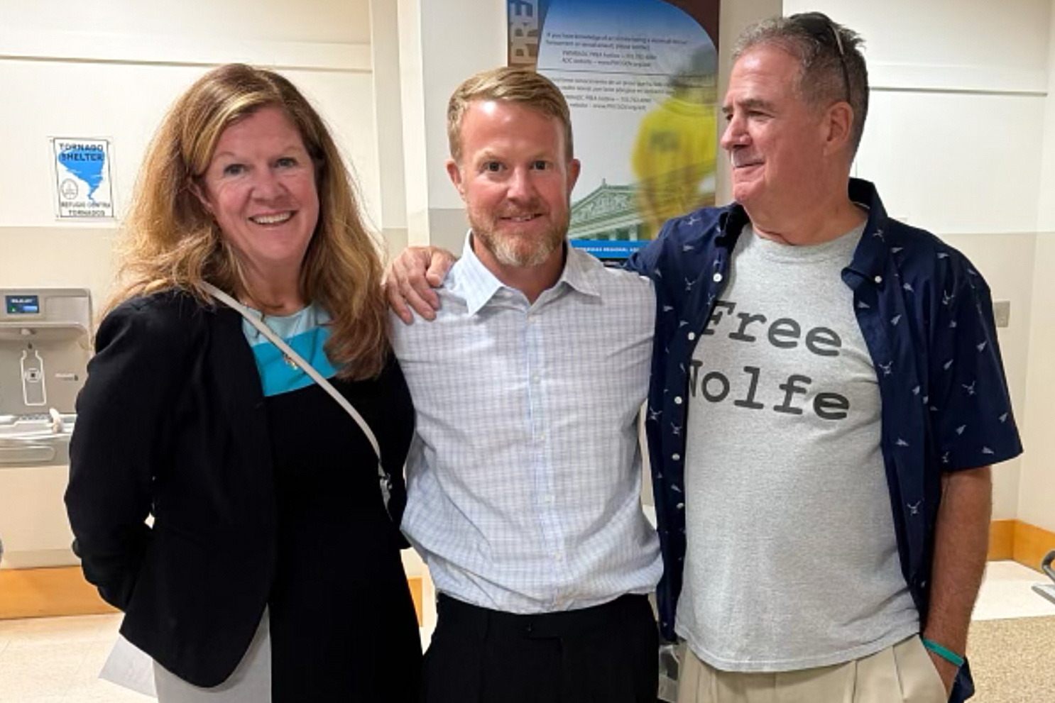 In this photo taken with a smartphone and provided by Erin Wolfe, Justin Wolfe, center, stands with...
