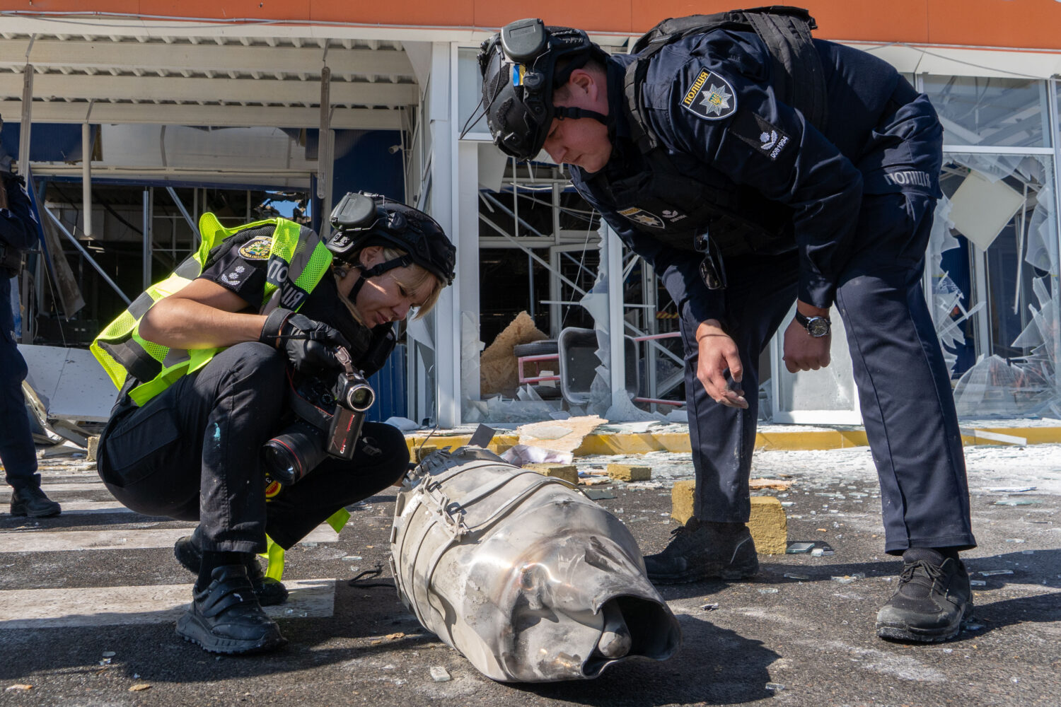 Police officers inspect fragments of a Russian drone after an air attack on a commercial infrastruc...