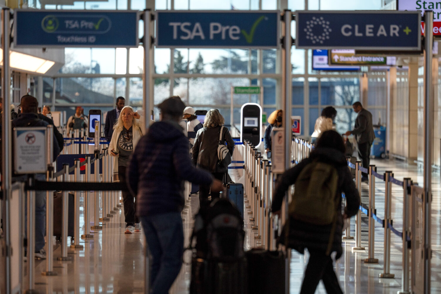 FILE - Travelers walk through a TSA security checkpoint at Reagan National Airport in Washington, M...