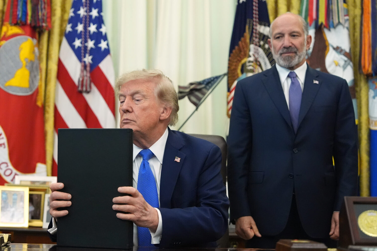 President Donald Trump listens before signing executive orders in the Oval Office of the White Hous...