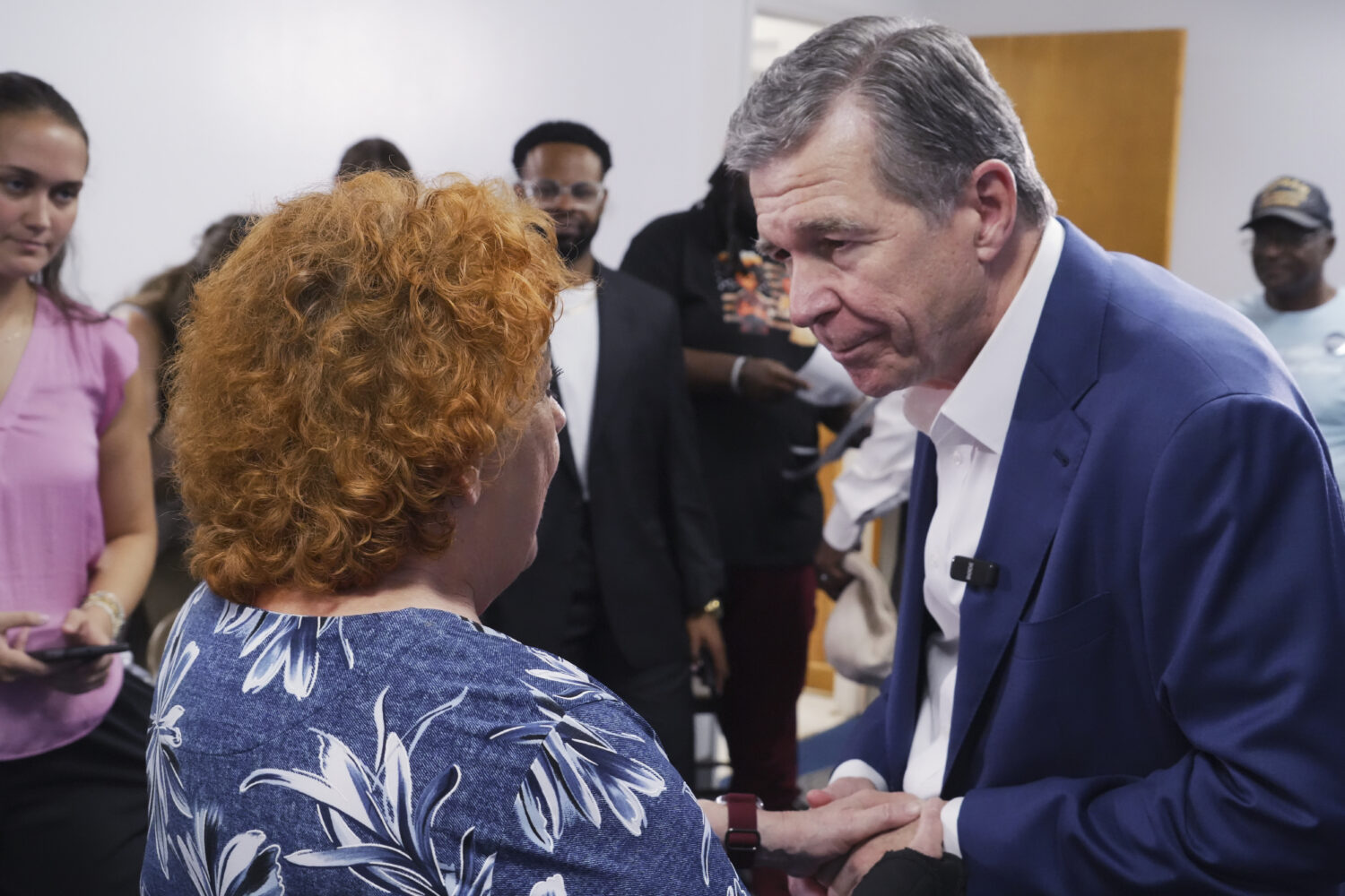 Former Democratic Gov. Roy Cooper, who is running for U.S. Senate, holds hands with a woman followi...