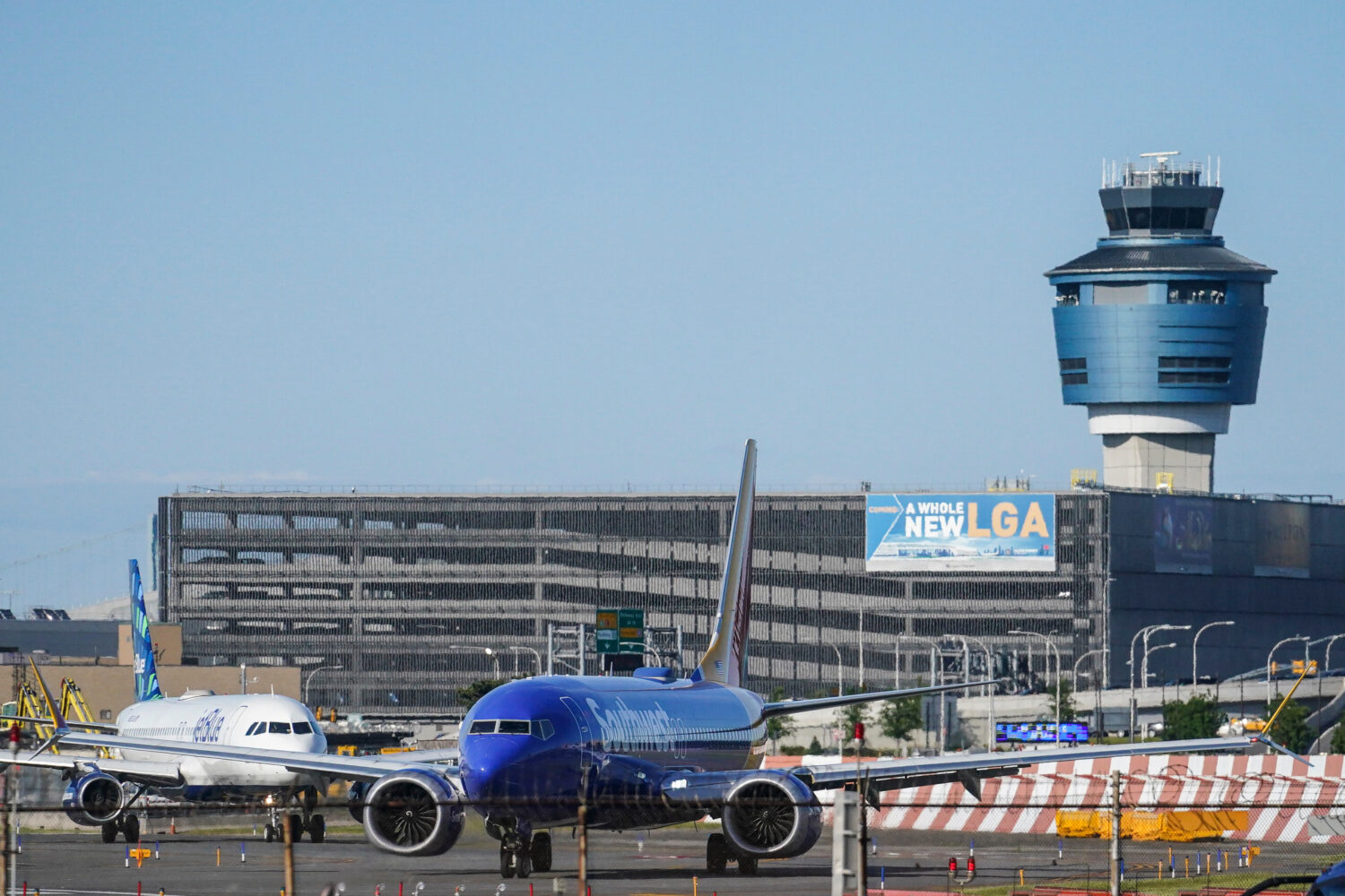 FILE - LaGuardia Airport's air traffic control tower, right, is shown as planes line-up for take-of...