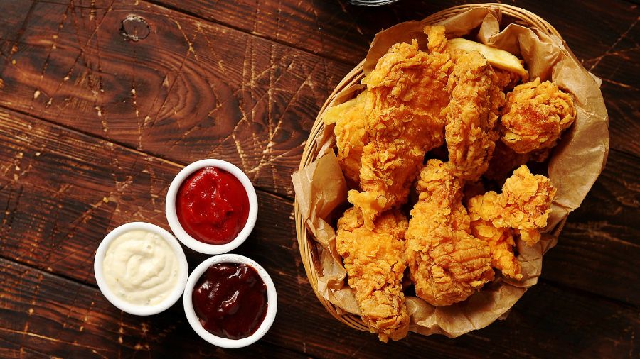 A basket of fried chicken, accompanied by small bowls of sauces. (Photo: Daniel_Dash via Envato)...