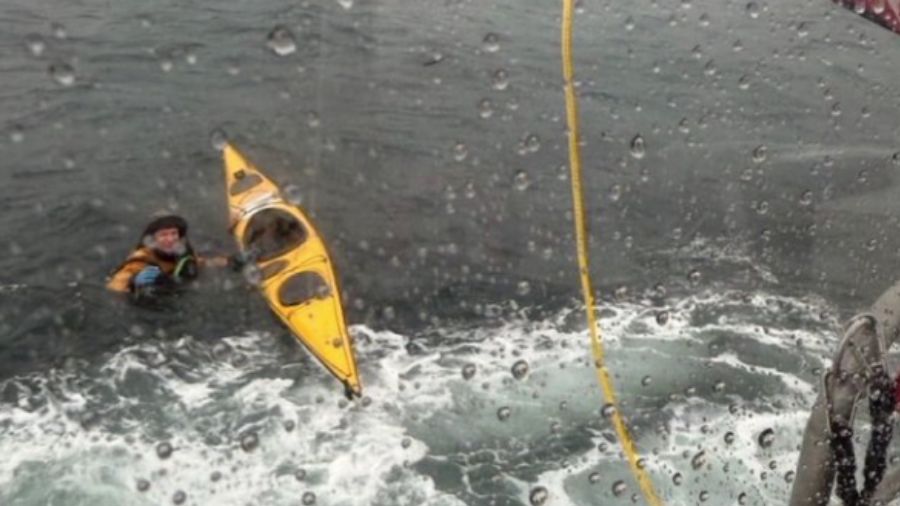 A Coast Guardsman tosses a rope to a kayaker in distress after the kayaker's boat overturned north ...