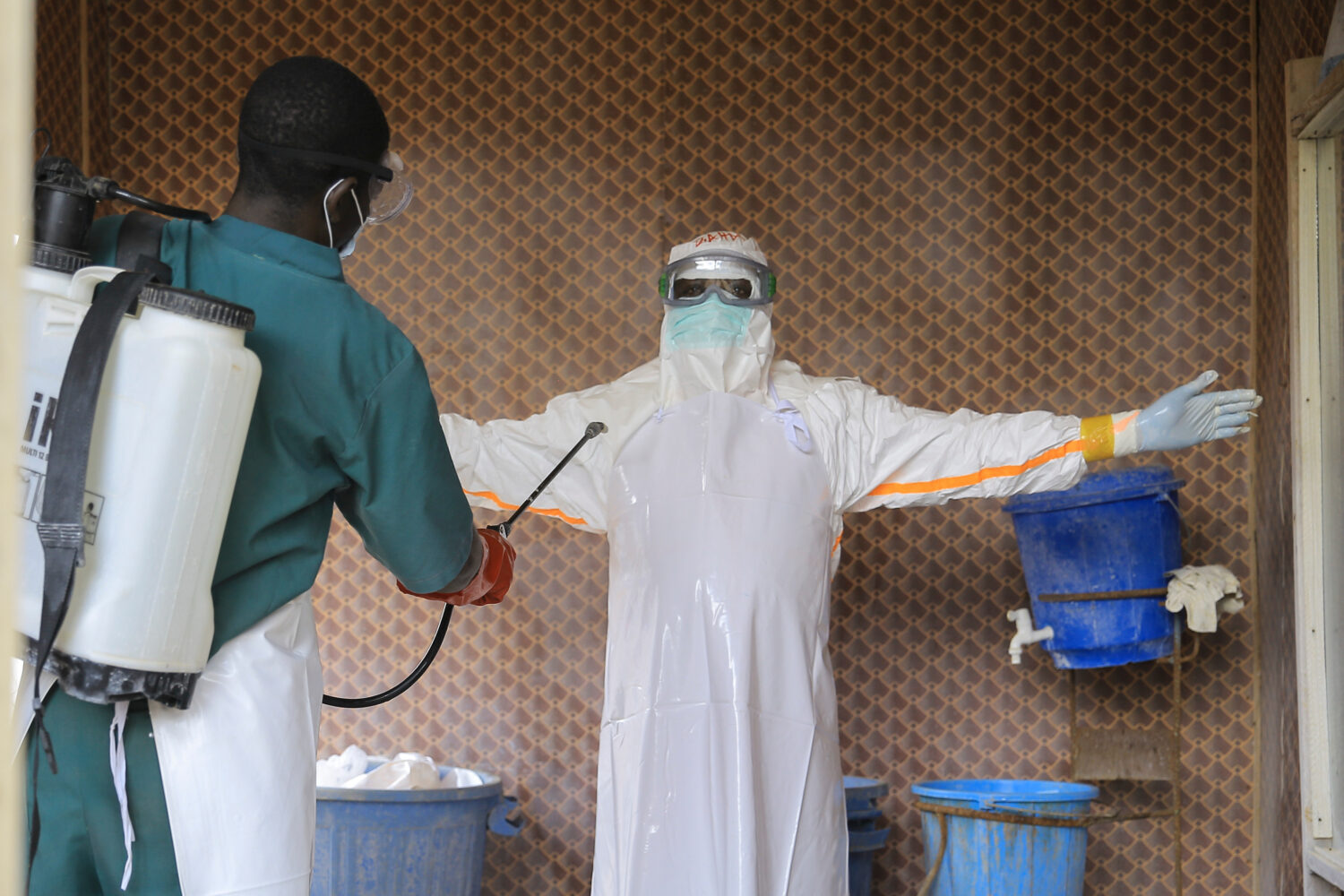 A healthcare worker in protective clothing is disinfected by a colleague inside a treatment center ...