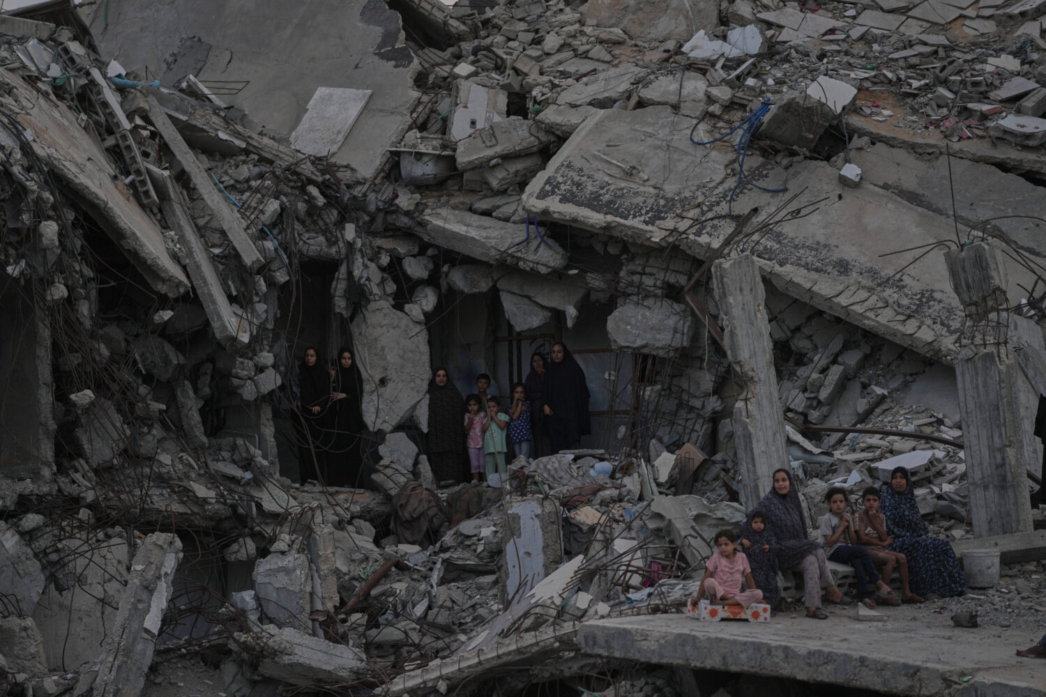 Palestinian women and children watch the Palestine Strongman Championship from among the rubble of ...