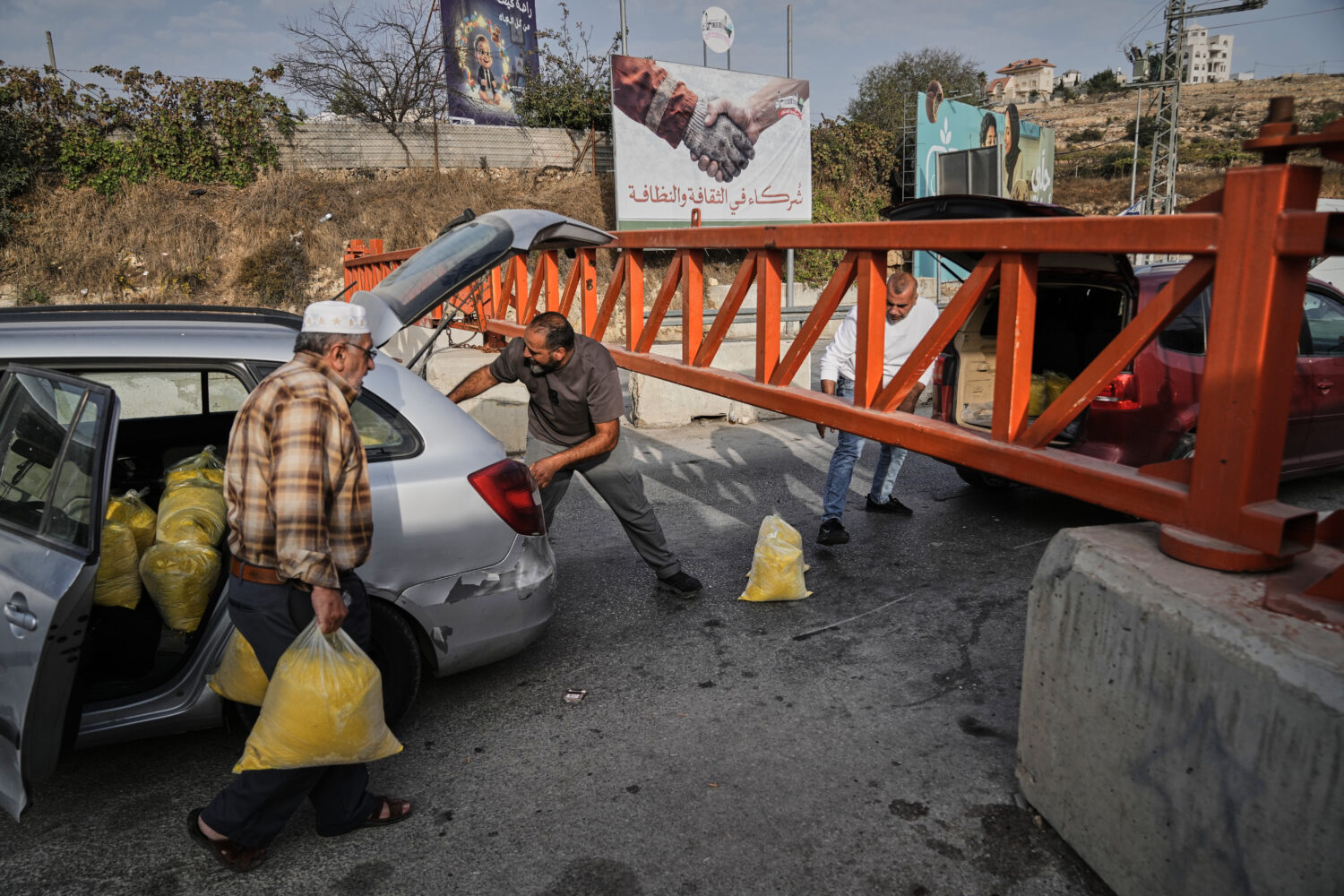 Palestinians transport bags of semolina past a military gate closed to vehicles during an Israeli a...