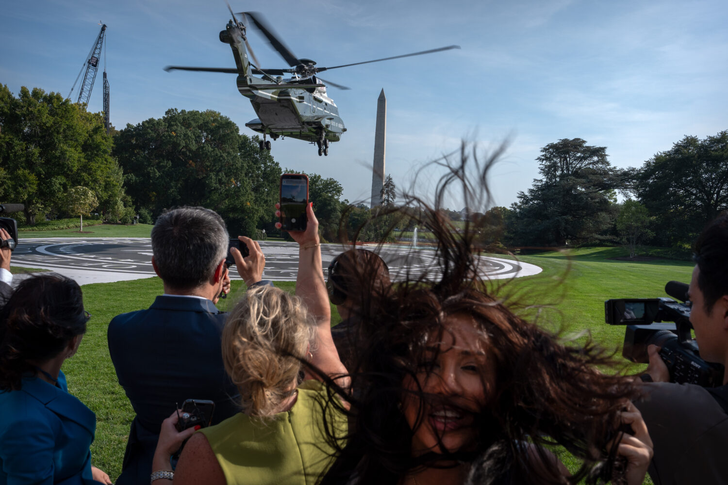 Members of the press watch as Marine One with President Donald Trump aboard lifts off from the Sout...