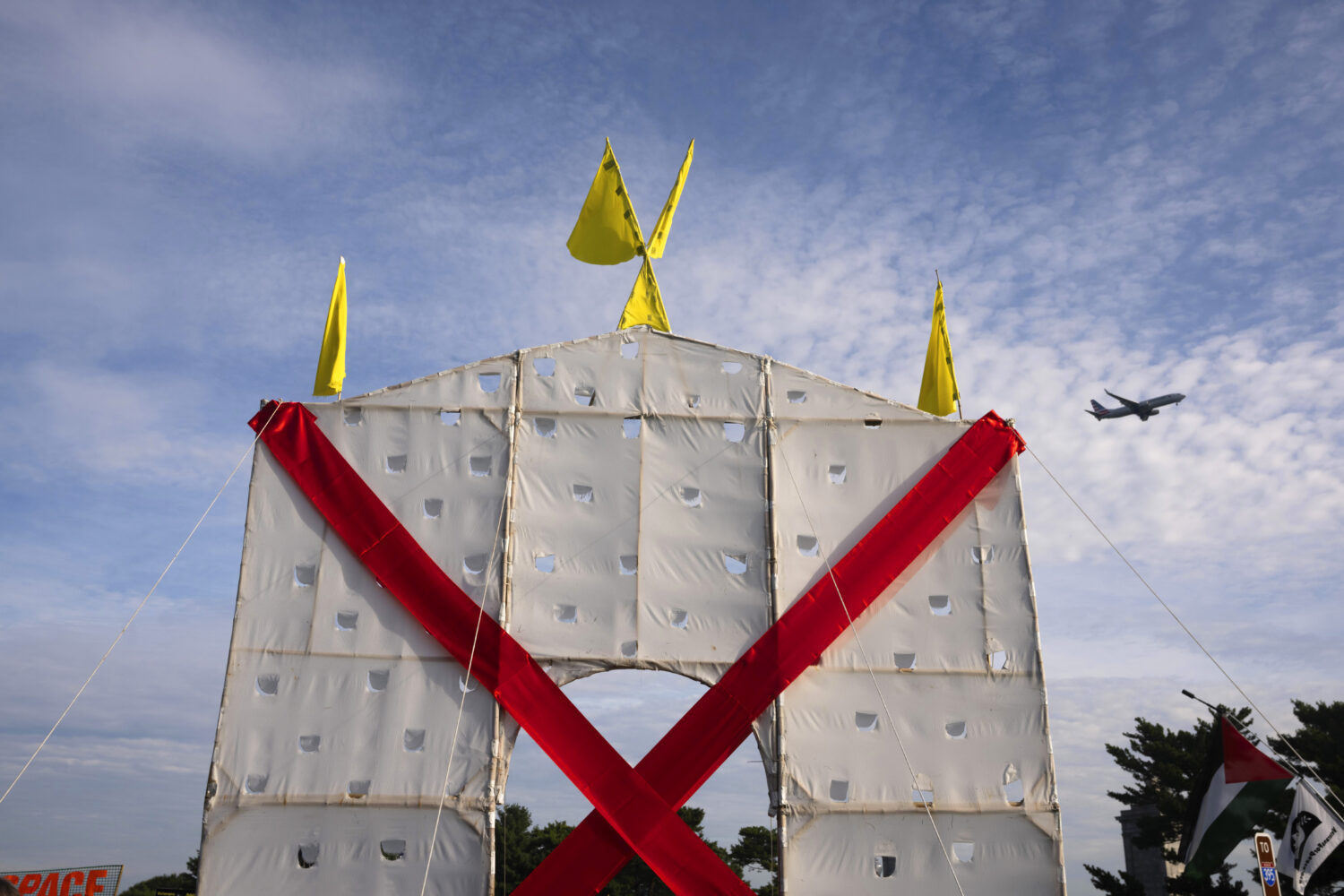 A plane flies over an anti-arch structure lifted up by demonstrators at Memorial Circle to protest ...