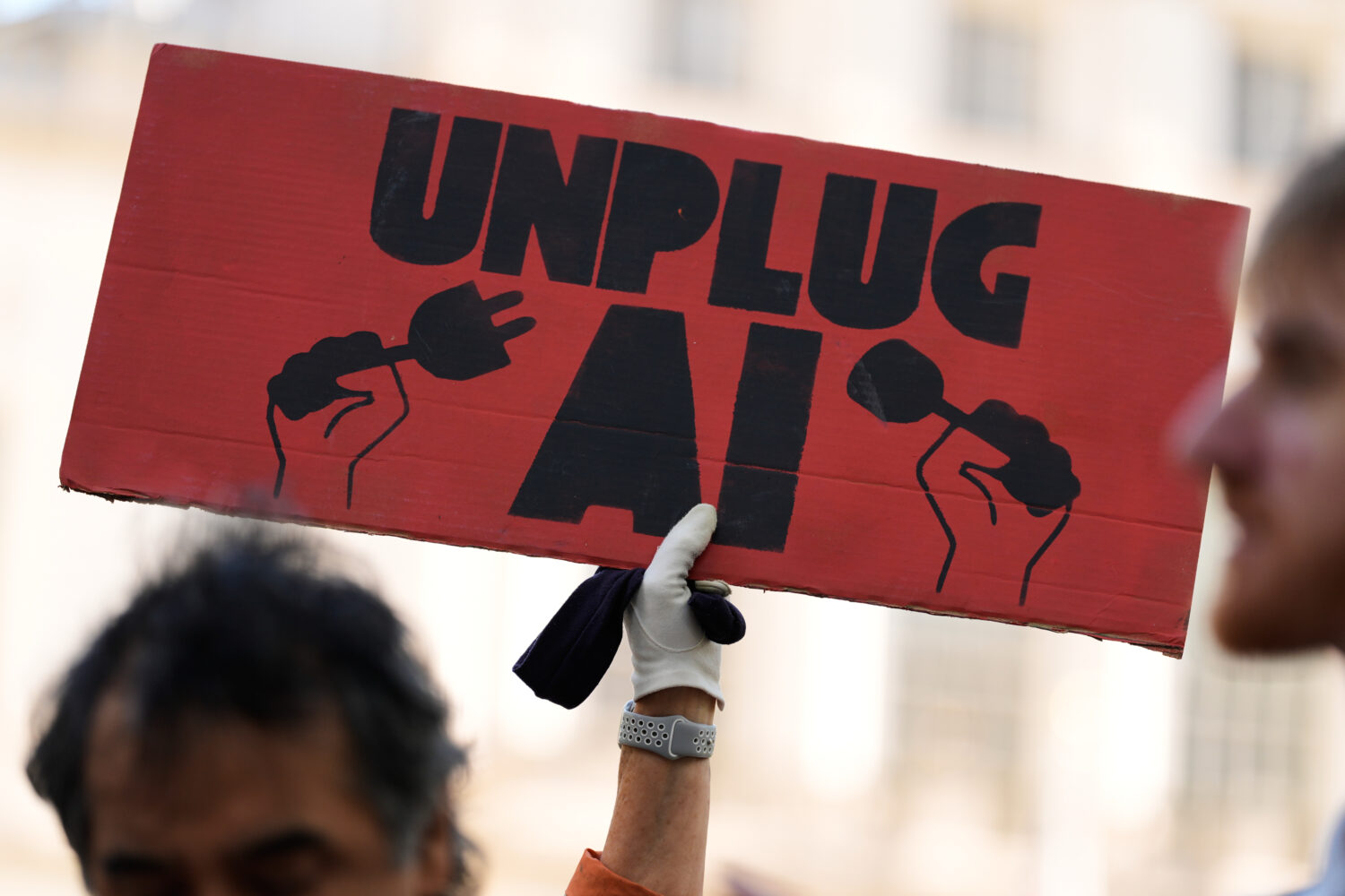 FILE - A small group of people supporting restrictions on artificial intelligence hold up signs in ...