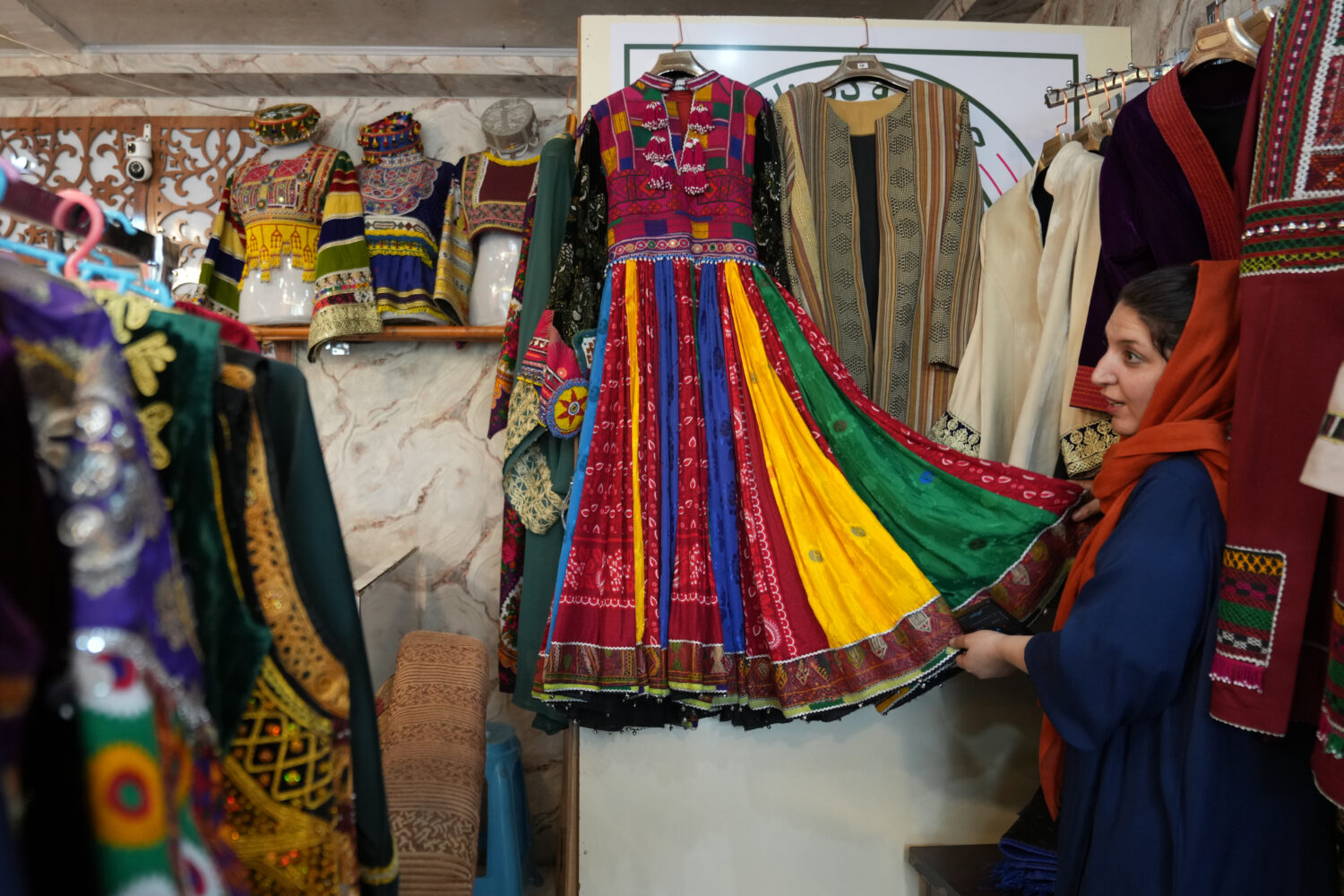 Tahmina Mangal displays a traditional Afghan dress at her clothing shop in Kabul, Afghanistan, Sund...