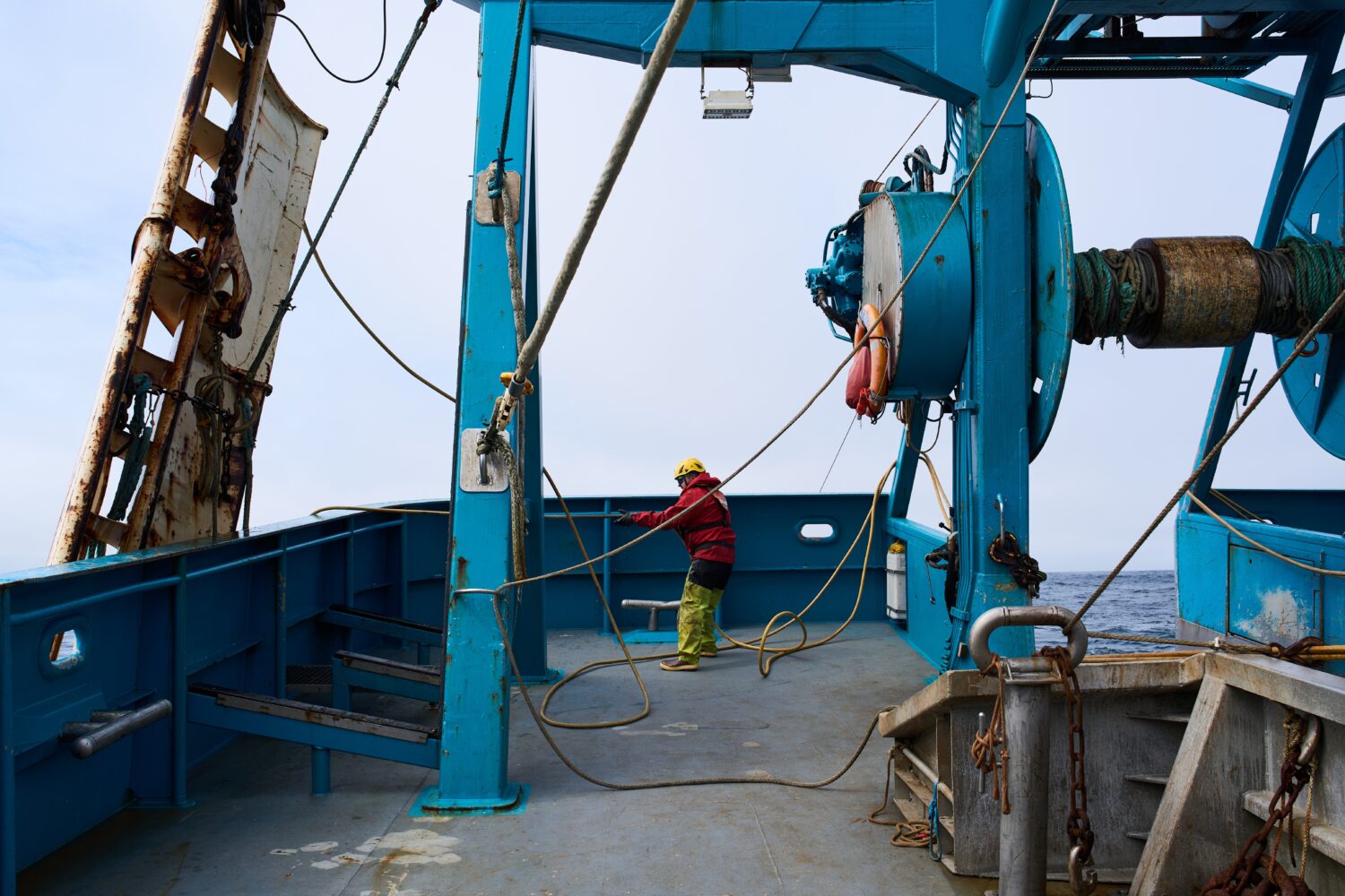 Deckhand Justin Schramm lifts trawl doors, which help spread the mouth of the net open, from the Be...
