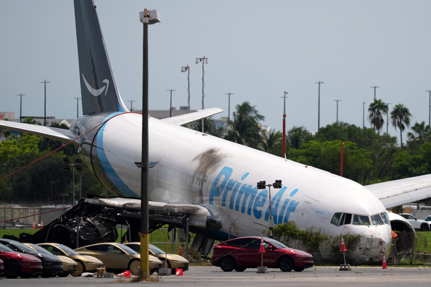 An Amazon cargo plane lies damaged near a parking lot two days after overshooting a runway at Miami...