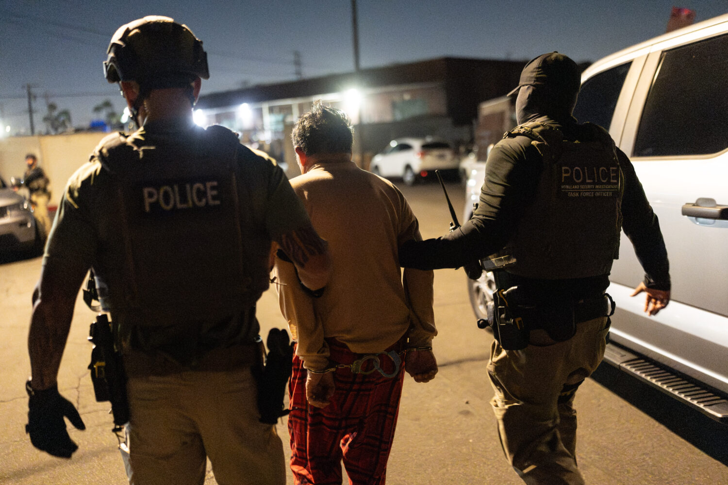 Homeland Security Investigations task force officers escort a suspect accused of illegally register...