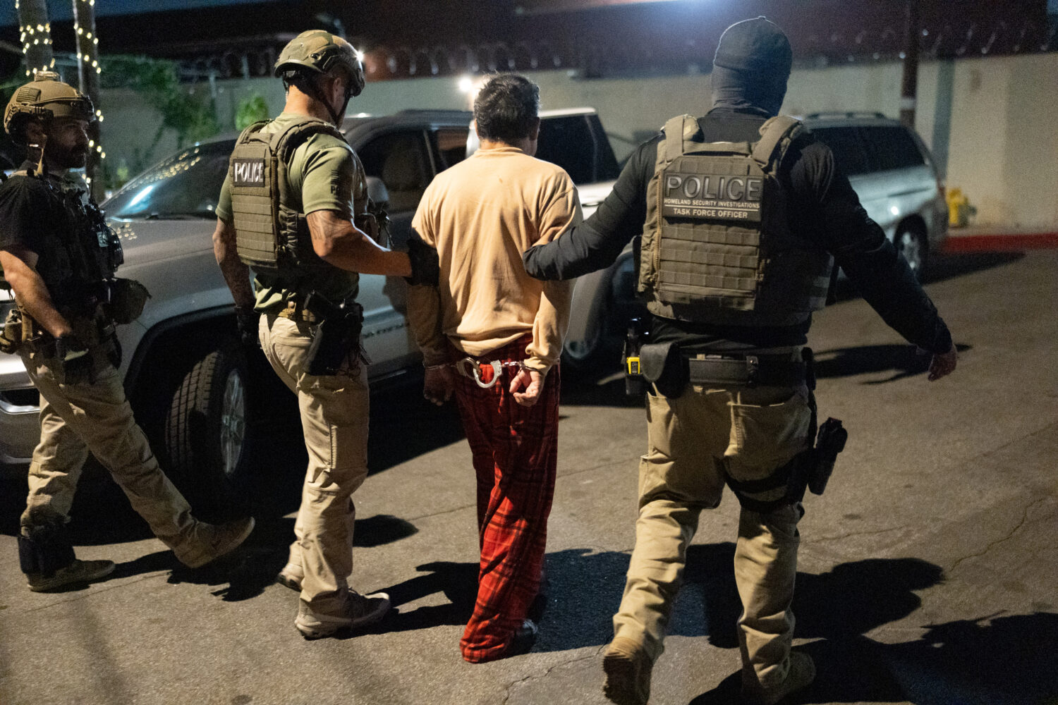 Homeland Security Investigations task force officers escort a suspect accused of illegally register...