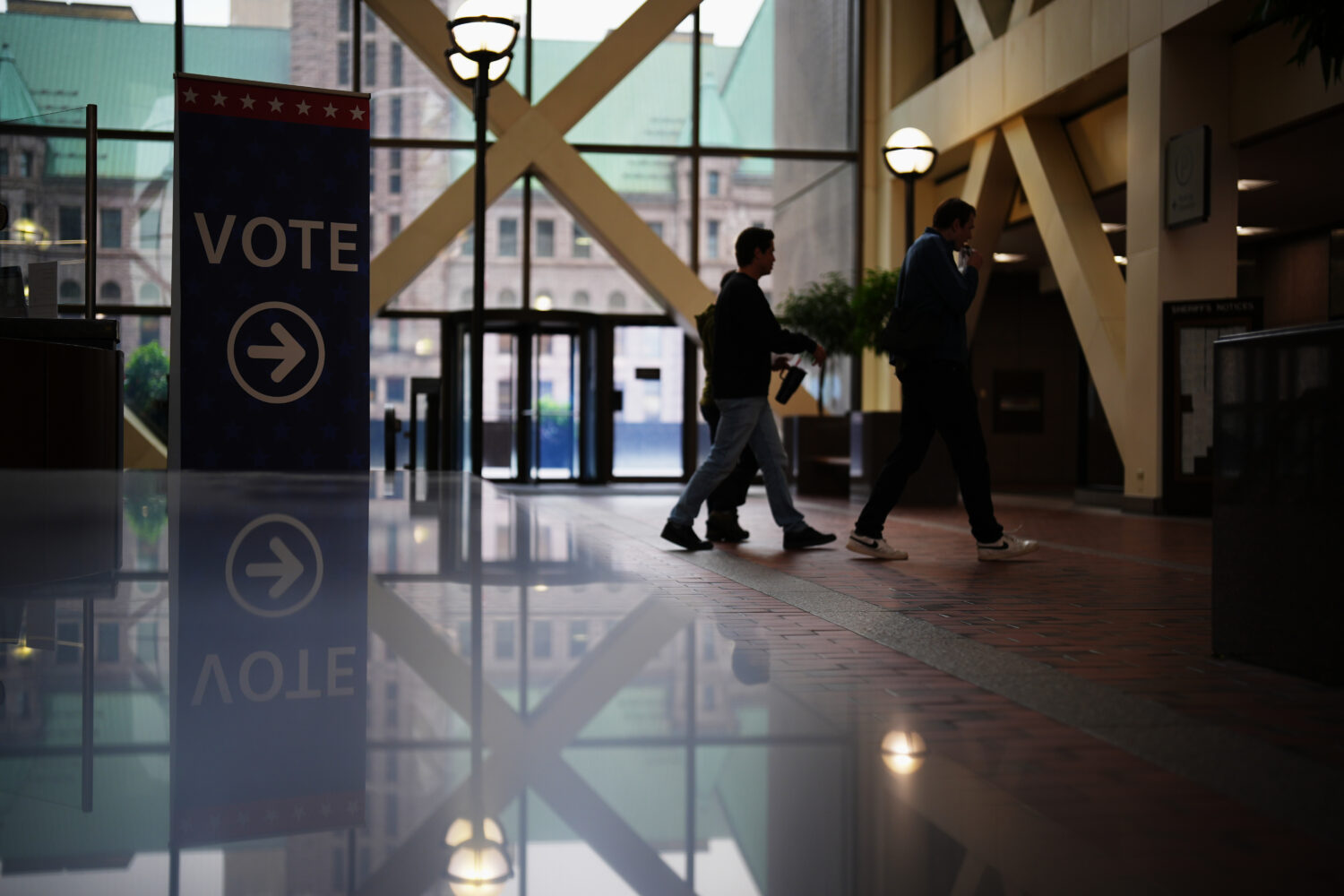 People walk past a sign directing voters on the first day of early voting in Minnesota at the Elect...
