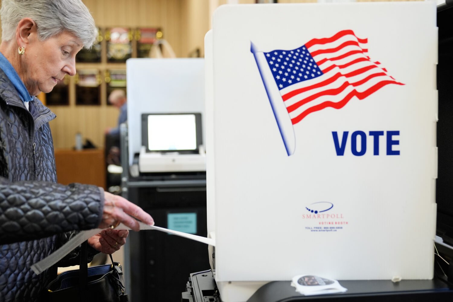 A woman feeds her ballot into a scanning machine at an early voting site in Haverstraw, N.Y., Monda...