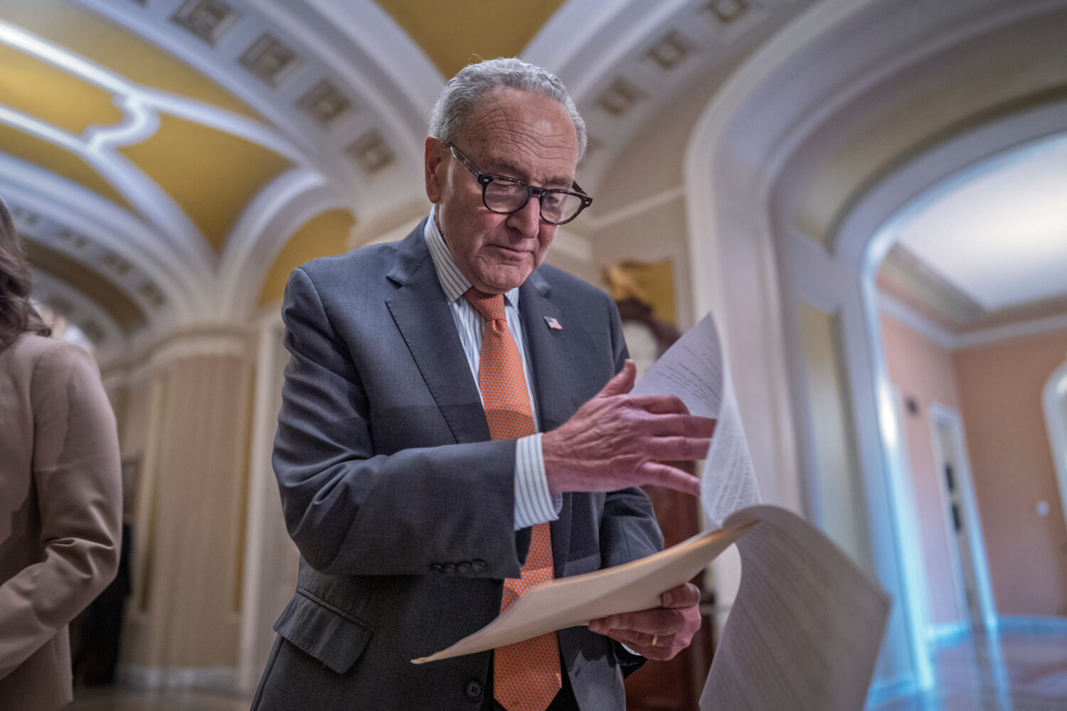 Senate Minority Leader Chuck Schumer, D-N.Y., looks over his notes as he speaks with reporters afte...