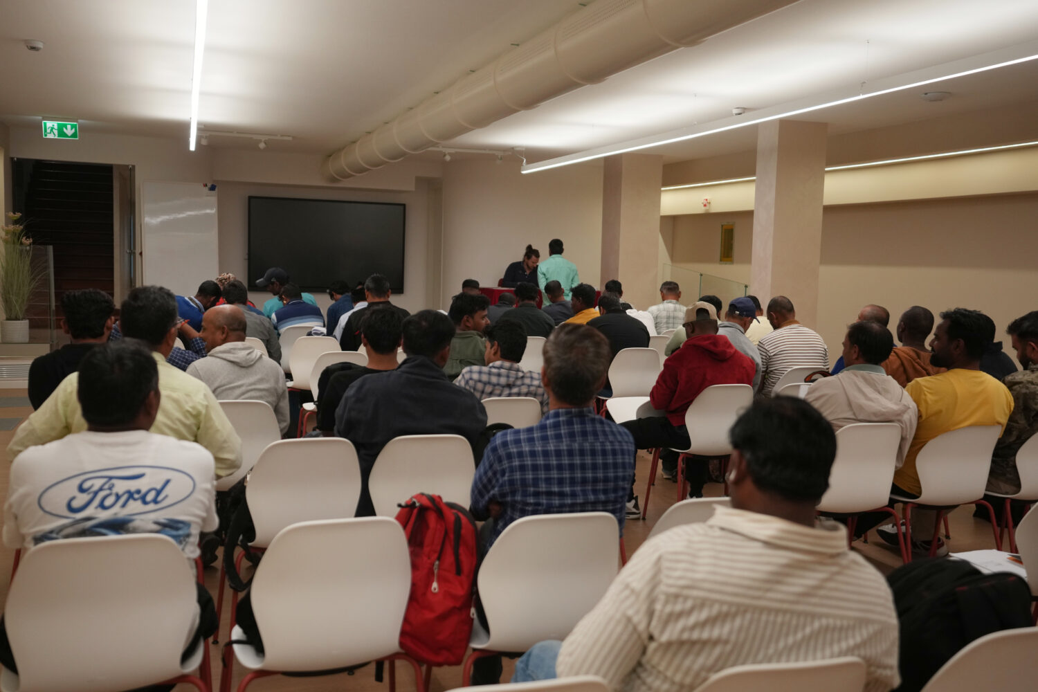 Caddell workers gather in a hotel conference room to wait their turn to sign an agreement for compe...