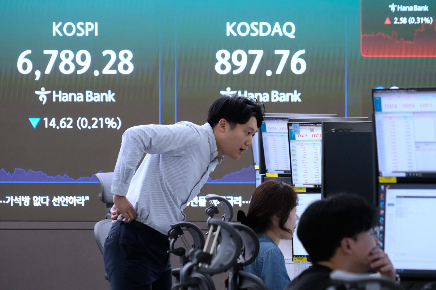 Traders watch monitors near a screen showing the Korea Composite Stock Price Index (KOSPI) at the f...