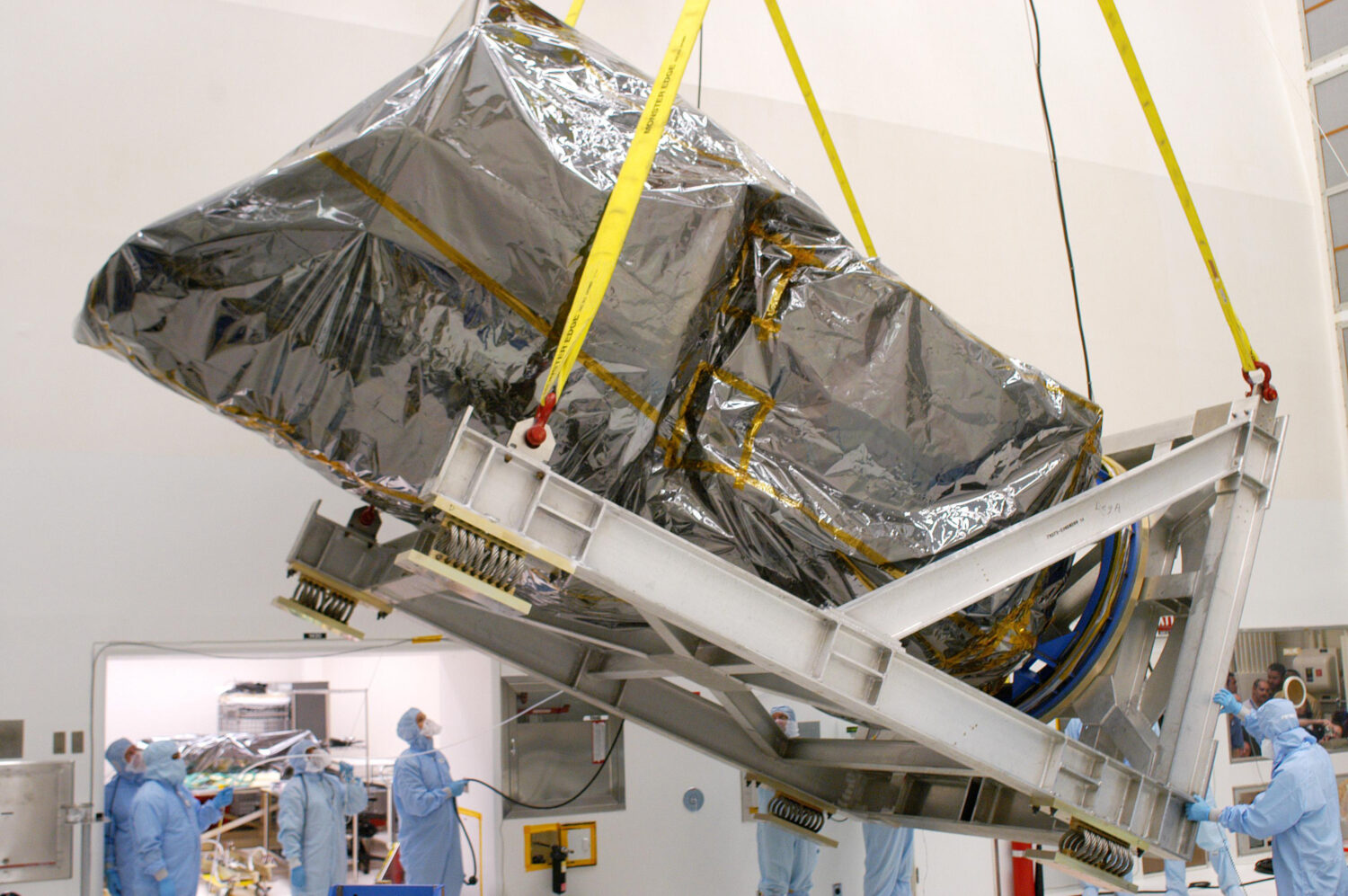 This photo provided by NASA shows an overhead crane raising the Swift spacecraft, wrapped in a prot...