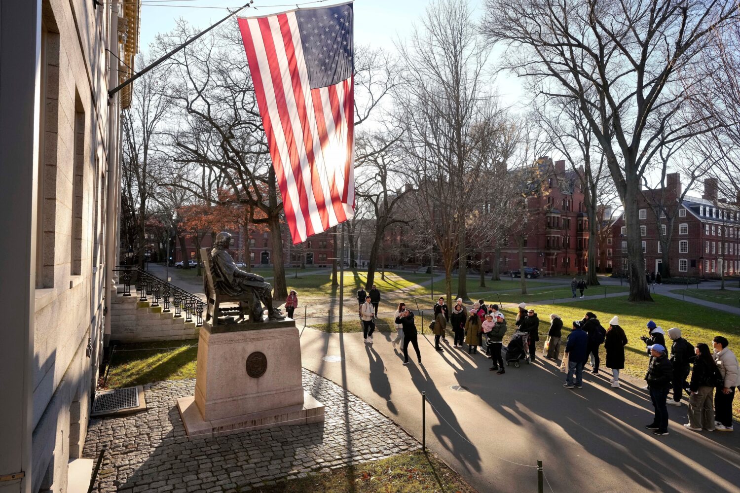 FILE - People take photos near a John Harvard statue on the Harvard University campus, Jan. 2, 2024...