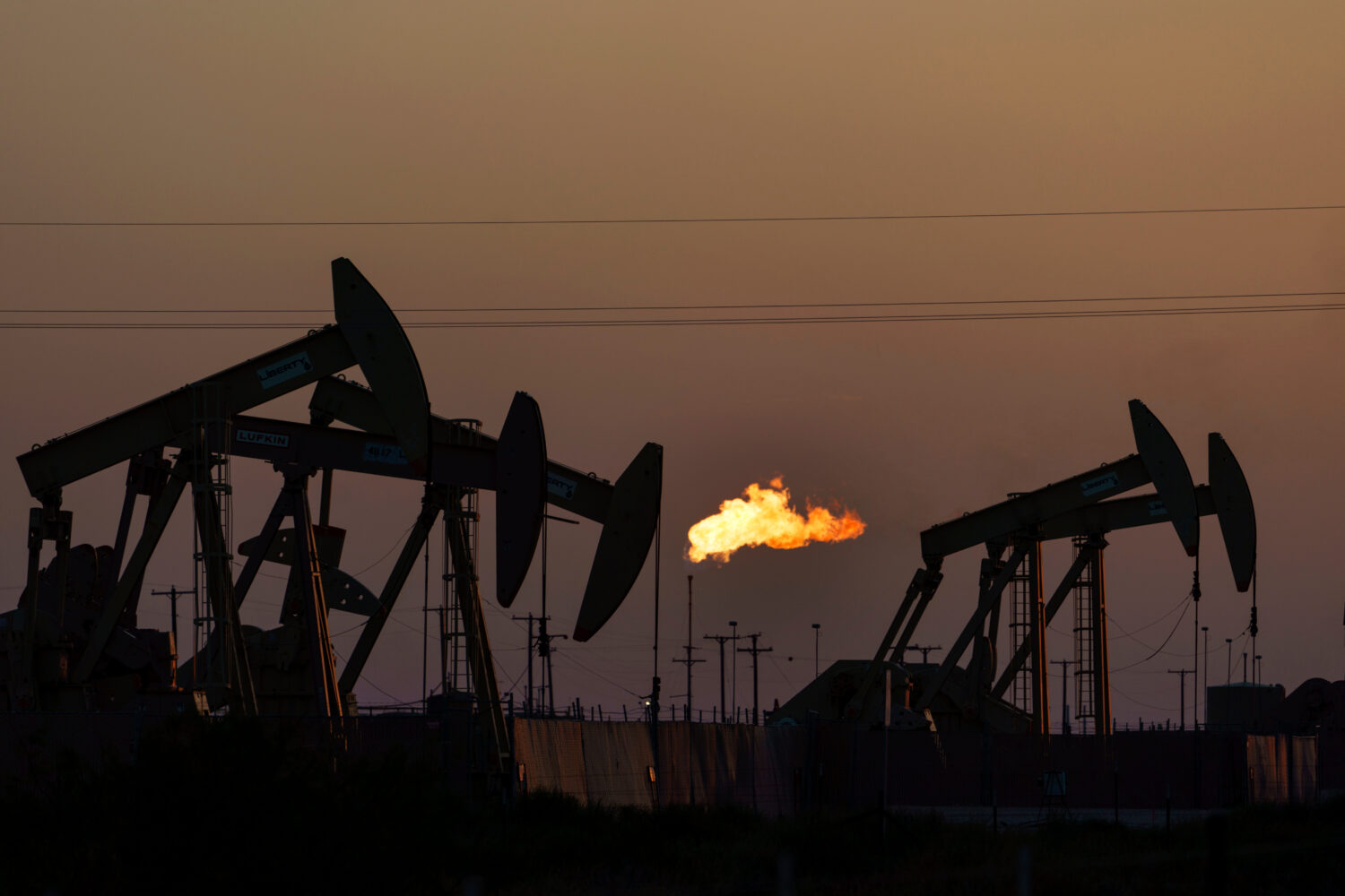 FILE - A flare burns off methane and other hydrocarbons as oil pumpjacks operate in the Permian Bas...