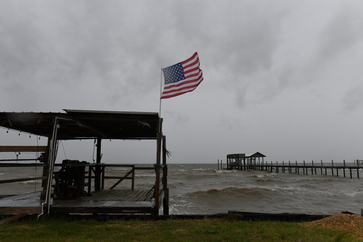 An American flag flaps in the wind generated by the effects of Isaias on an empty beach on Friday, ...