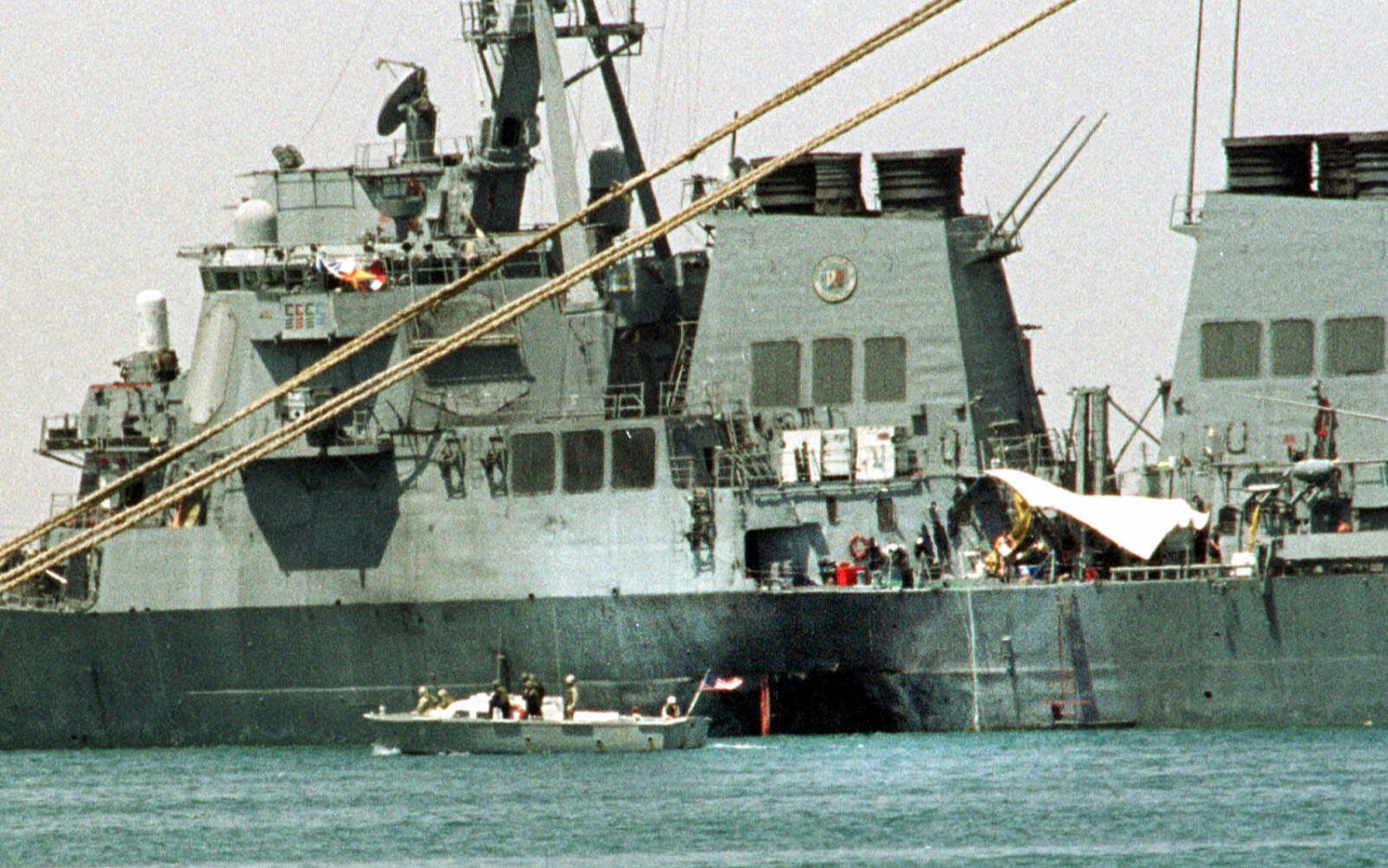 FILE - A small boat guards the stricken USS Cole in Aden, Yemen, Oct. 20, 2000. (AP Photo/Hasan Jam...