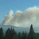 A large plume of smoke is seen rising high into the sky causing poor visibility.