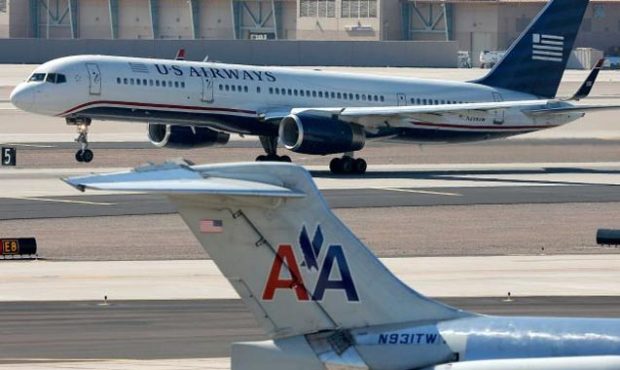 In this Thursday, Feb. 14, 2013, file photo, a U.S. Airways jet passes an American Airlines jet at ...