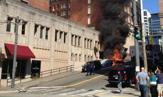 A car explodes after it was struck by a recycling truck Tuesday afternoon in downtown Seattle. (Pho...