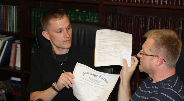 Mikey Hall and his husband, Eli, show reporters a couple of their marriage certificate during a new...