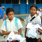 A World Vision worker distributes T-shirts to school children at a World Vision Area Development Program in Nicaragua following the Patriots 2008 Super Bowl loss.