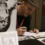 An artist works on sketches while selling prints at a booth at Emerald City Comicon at the Washington State Convention Center in Seattle, on Saturday, March 29, 2014.
