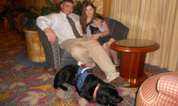Carlos sits with his wife Elana, young son, and his dog, Fiona....