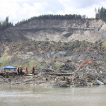 A crew works on the bank of the North Fork Stillaguamish River, April 18, 2014. A spotter checks the material pulled from the mud by a heavy equipment operator. One month after the slide devastated this community, crews are still searching for at least two missing people.
