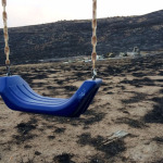 In the foreground, a child's swing set sits relatively unscathed while the family's home, seen in the background, was destroyed after a firestorm passed through this rural area outside of Pateros, Washington. 