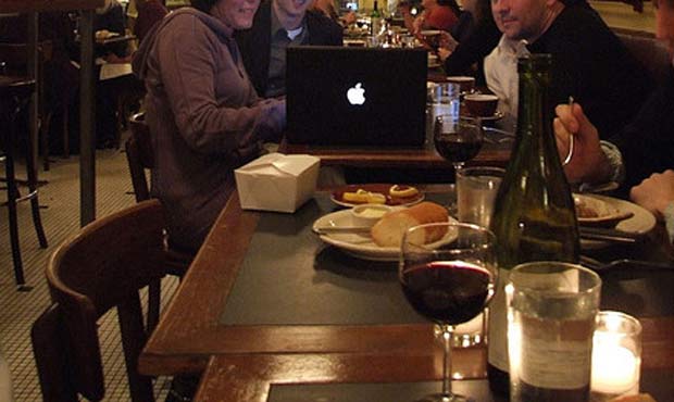 Seattle diners huddle around a laptop while eating a meal at a lovely downtown French bistro. (Jeff...